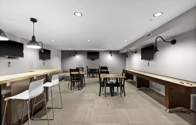 a large room with tables chairs and a bar with chairs and televisions