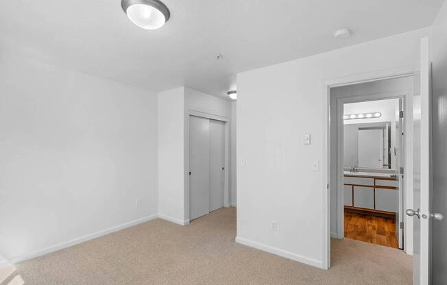 a bedroom with white walls and a door to a bathroom