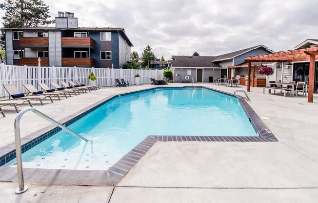 A swimming pool surrounded by a concrete floor and a metal ladder. at Vibe, Kent, WA, 98030