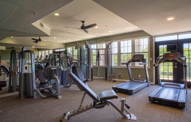 a gym with cardio equipment and windows