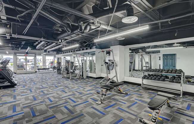 A gym with a variety of equipment including treadmills, weights, and exercise machines.