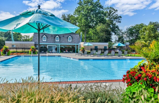 Outdoor swimming pool with lounge chairs and umbrellas at Franklin Commons apartments for rent in Bensalem, PA