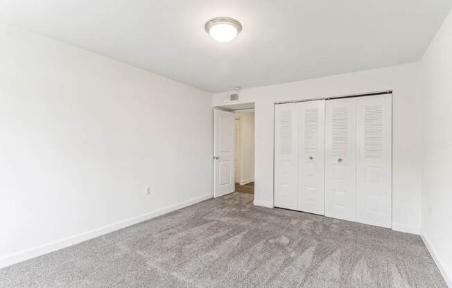 a bedroom with white walls and a door to a closet