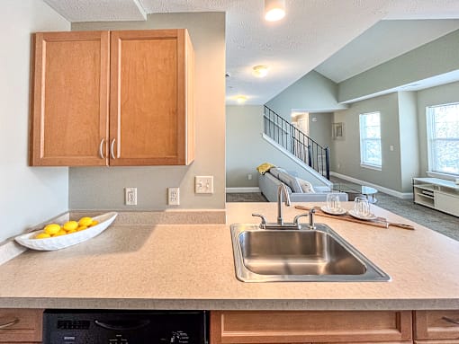 View from kitchen sink and breakfast bar towards living area of great room and stairs to second floor loft area