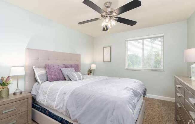 A bedroom with a bed, nightstands, and a ceiling fan.