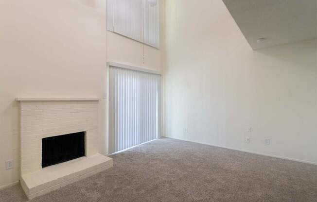 A living room with white brick fireplace and white ceiling fan in a 717 square foot 1 bedroom, 1 bath loft apartment home at Canyon Creek Apartments in Dallas Midtown neighborhood of Dallas, TX.