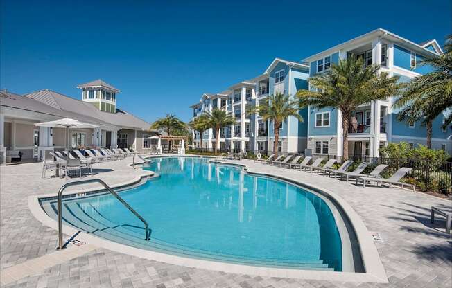 A large swimming pool surrounded by lounge chairs and palm trees.