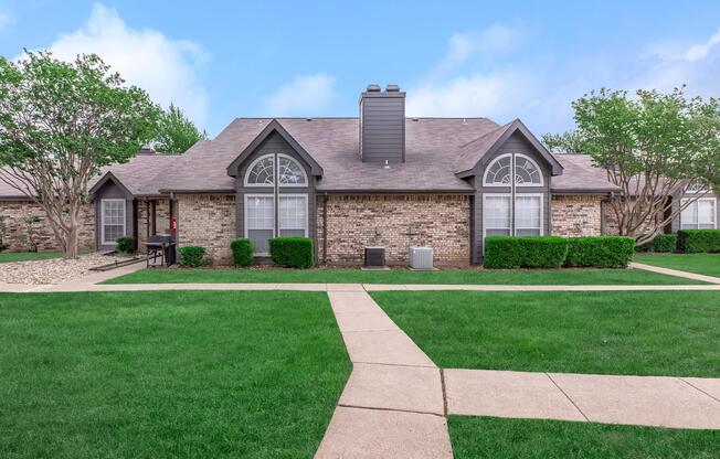 a house with a lawn in front of a brick building