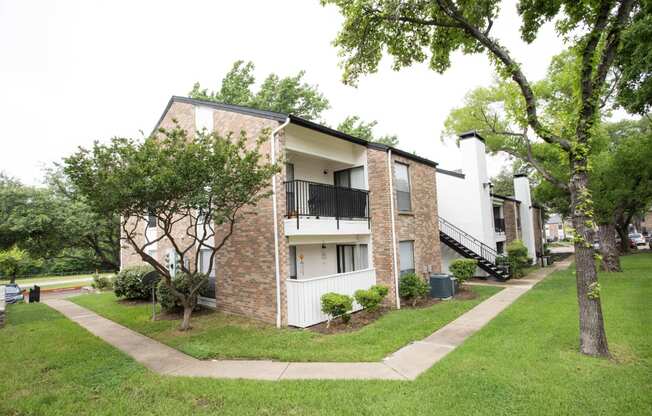 the outlook of an apartment building with a lawn and trees