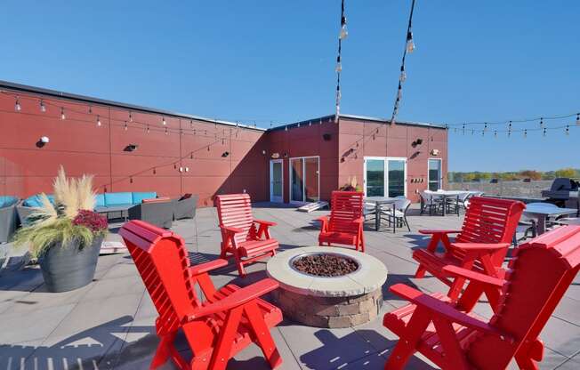 a roof terrace with red chairs and a fire pit