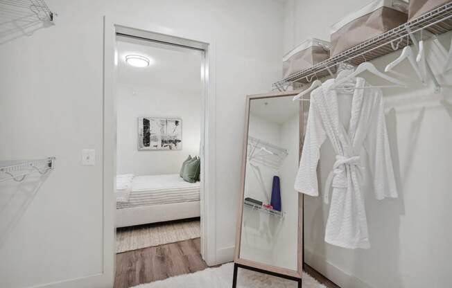 a bathroom with a mirror and a closet with robes and a bed at Sinclaire on Seminary, Virginia, 22311