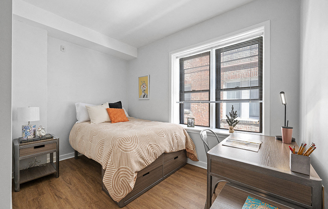 Spacious furnished student apartment bedroom with large windows, vinyl hardwood floors, and white walls