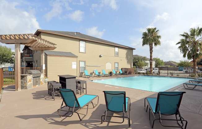 A pool area with chairs and a building in the background.
