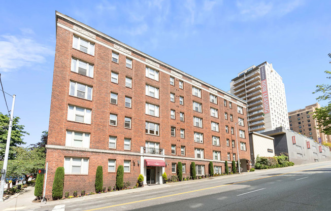 Street view of large brick property building with a street in front of it at Stockbridge Apartment Homes, Seattle, Washington 98101