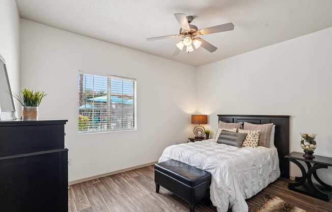 A bedroom with a bed, nightstand, and a window with blinds.