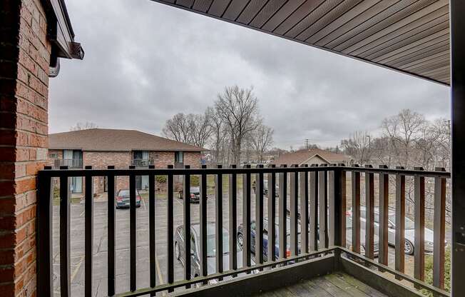 the balcony has a view of the parking lot and the house