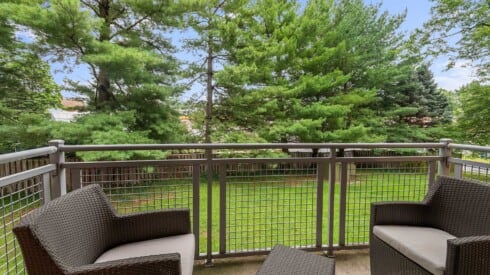 a balcony with chairs and a view of the trees