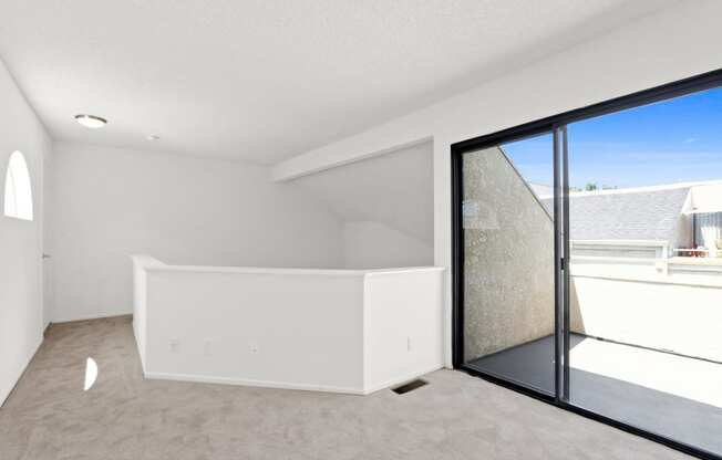 an empty living room with a large window and white walls