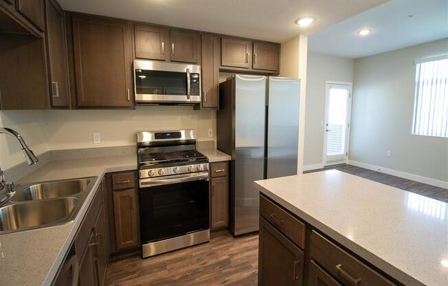 a kitchen with wooden cabinets and stainless steel appliances at Loma Villas Apartments, San Bernardino, California