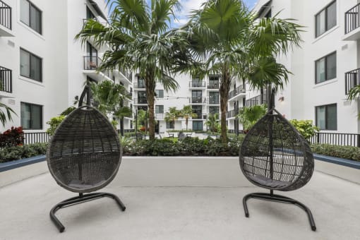 two chairs in front of an apartment building with palm trees