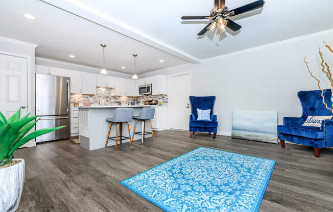 a living room with a kitchen and a ceiling fan