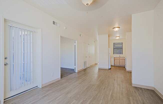 a spacious living room with white walls and wood flooring