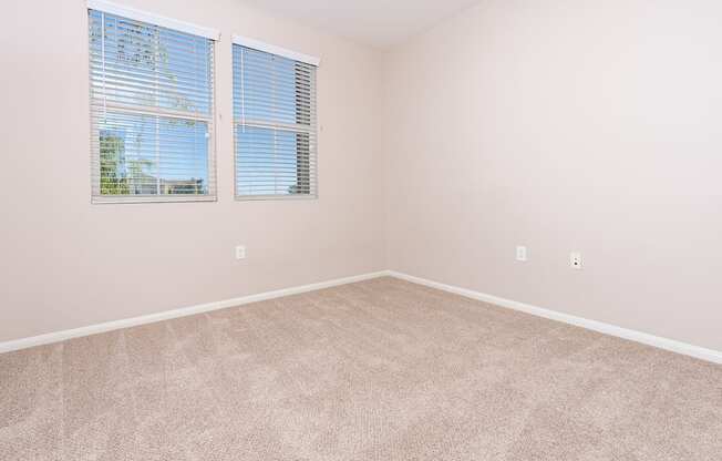 a bedroom with two windows and beige carpet