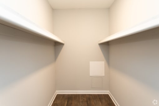 a room with two shelves and a white wall and a wooden floor