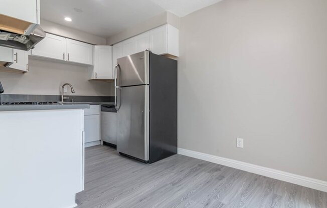 a white kitchen with a stainless steel refrigerator
