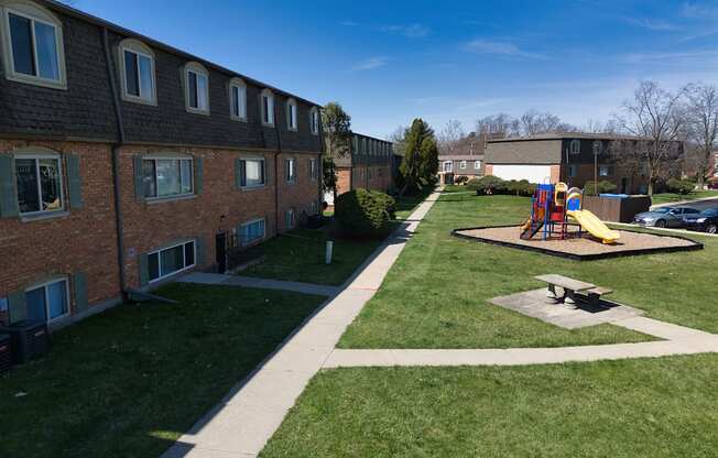 a playground in a yard in front of a brick building