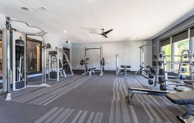 A spacious gym with a variety of equipment including a treadmill, weights, and a bench.