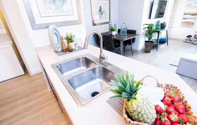 a kitchen sink with a pineapple and a basket of fruit