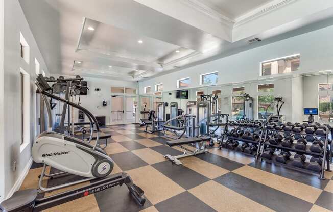 a gym with cardio equipment and weights on a checkered floor