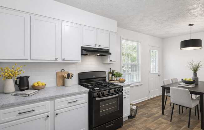 A kitchen with white cabinets and a black stove top.