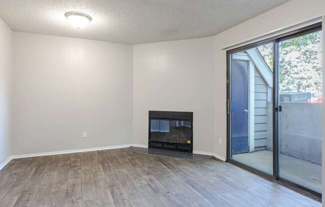 an empty living room with a fireplace and a sliding glass door