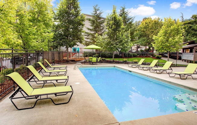 a swimming pool with chaise lounge chairs and trees