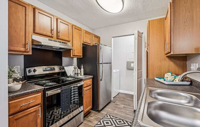A kitchen with wooden cabinets and a black and white patterned rug.