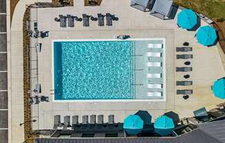 An aerial view of a swimming pool surrounded by lounge chairs and umbrellas.