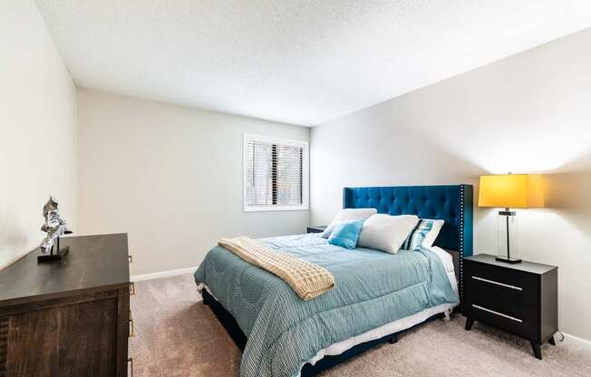 A bedroom with a bed, nightstand, and a lamp.