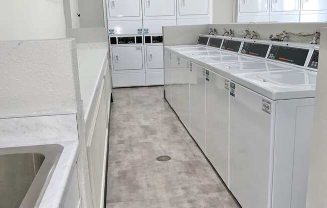 a large laundry room with white cabinets and appliances