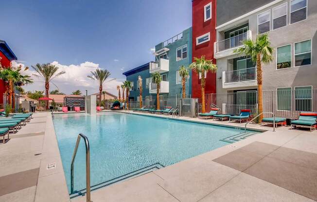 A swimming pool surrounded by palm trees and lounge chairs.