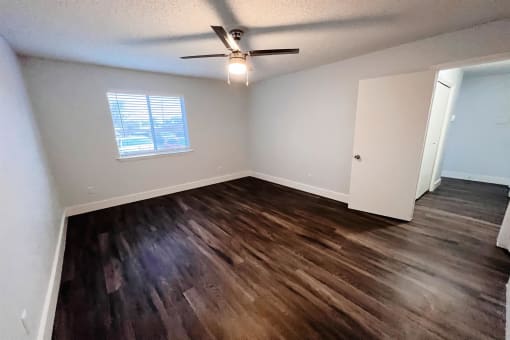 an empty living room with wooden floors and a ceiling fan