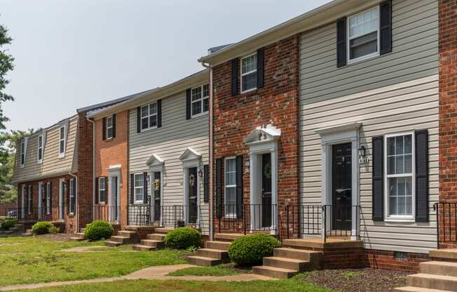 a row of town houses with steps and a lawn