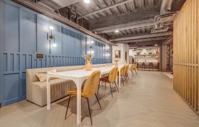 a long dining room with blue walls and a long table with yellow chairs