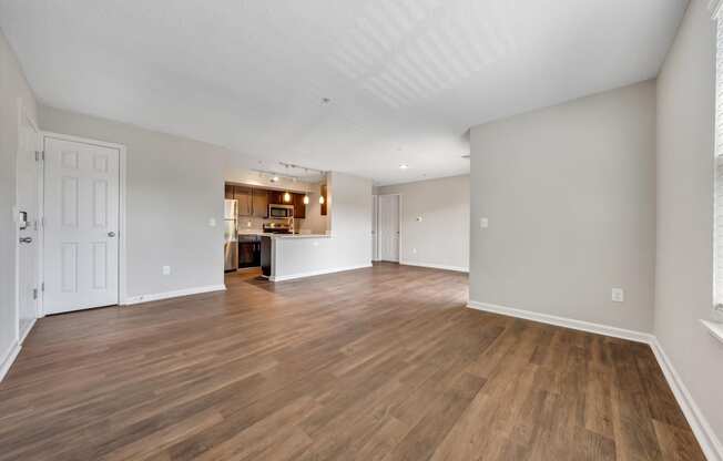 a spacious living room with hardwood floors and a kitchen in the background