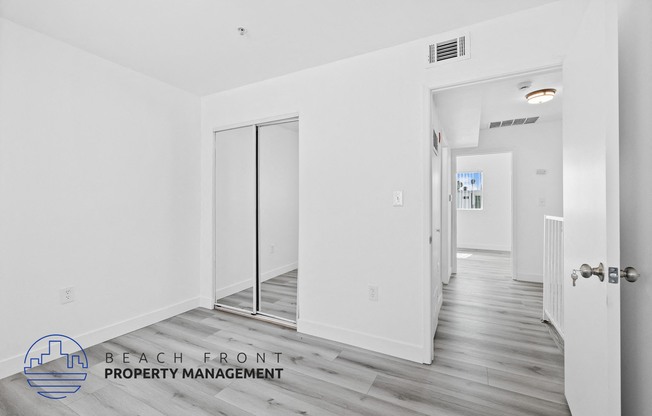 a renovated apartment with white walls and wood flooring and a hallway with white doors