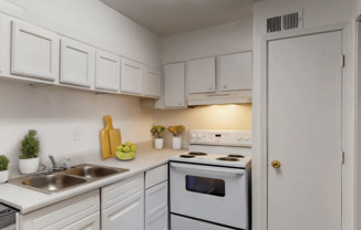 A white kitchen with a sink, stove, and cabinets.