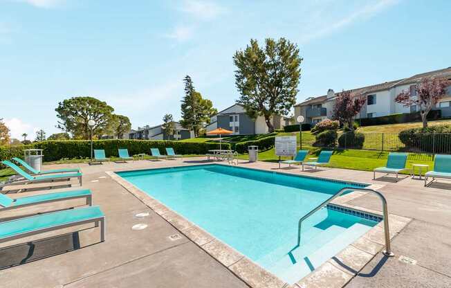 A swimming pool surrounded by lounge chairs and trees.