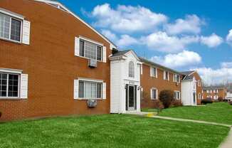Red brick apartment buildings with blue clouded sky and green grass