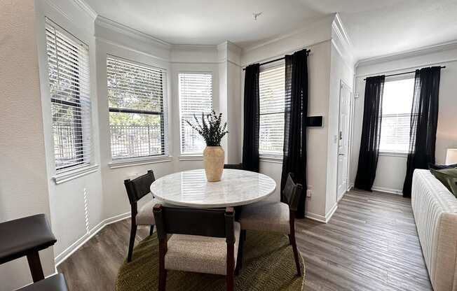 a small dining room with a table and chairs and windows